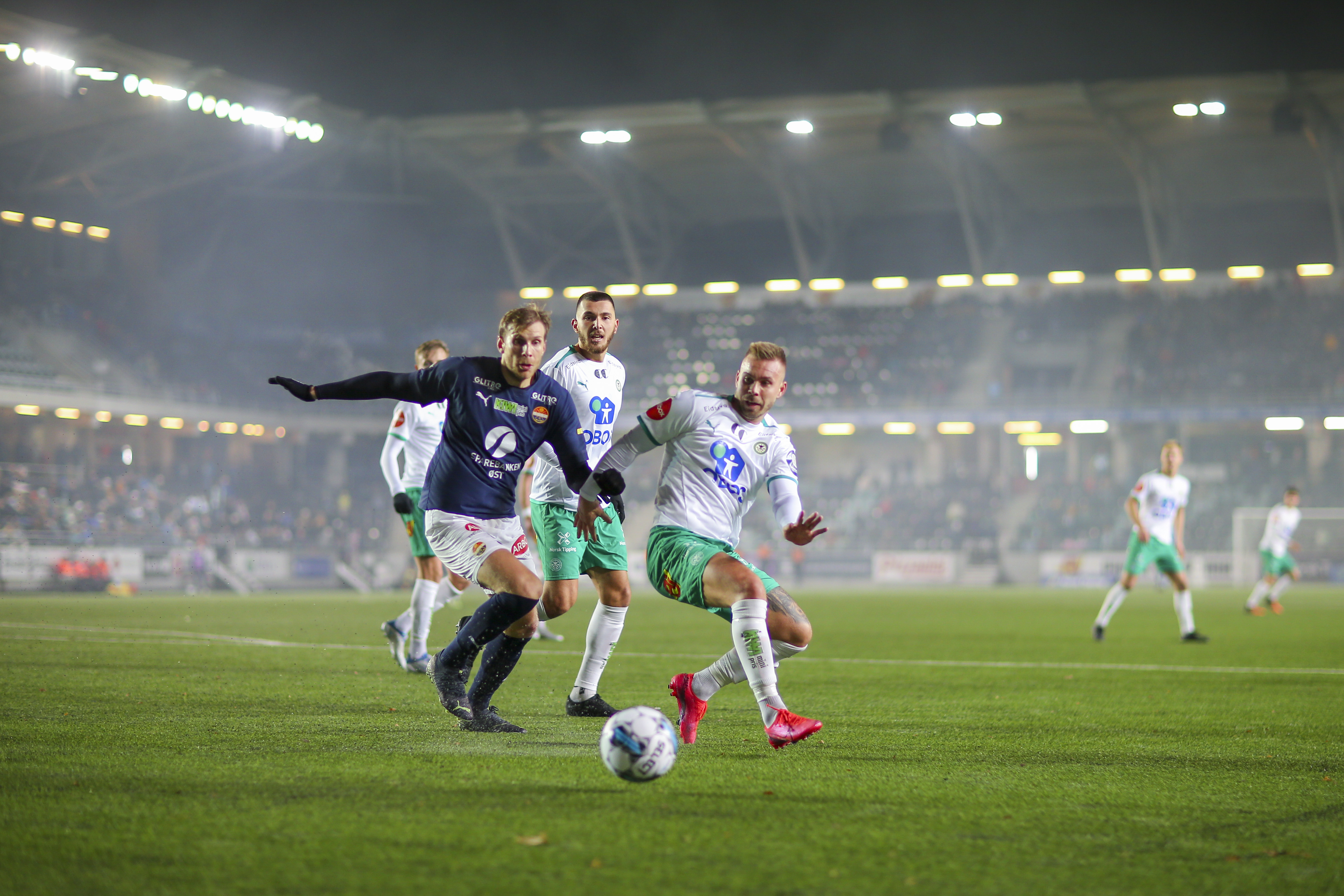 Fotballspillere i kamp under flomlys